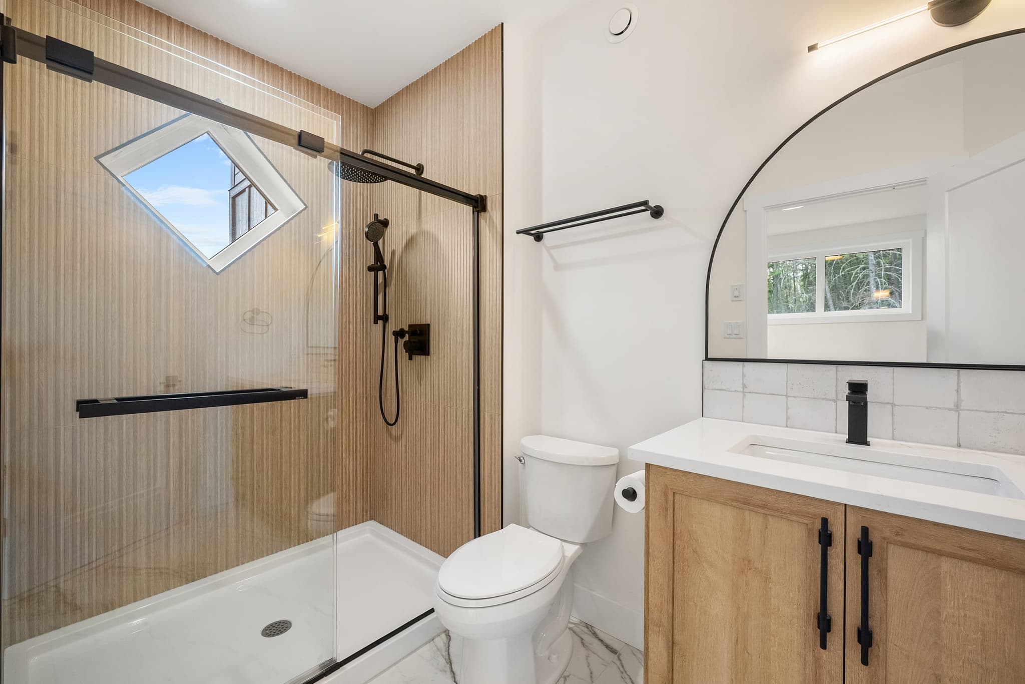 Guest bathroom with custom tile shower and arched mirror