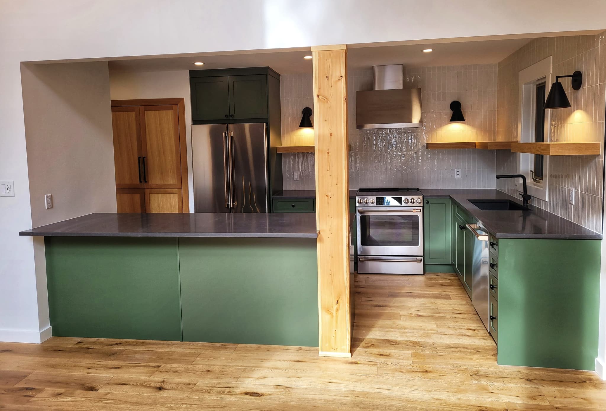 Modern kitchen remodel with deep-green cabinets and timber post