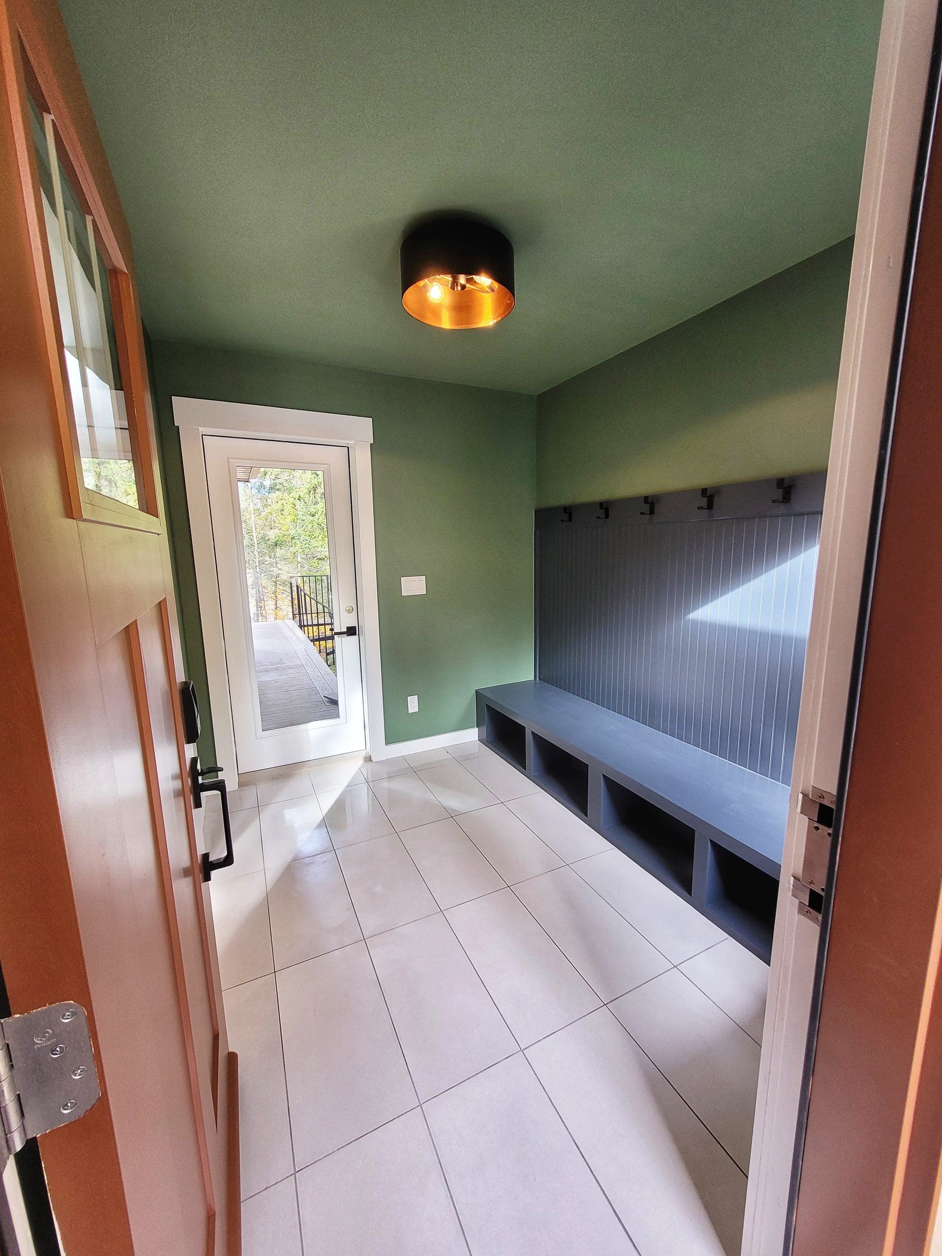 Cottage mudroom with green walls, ceiling and custom bench