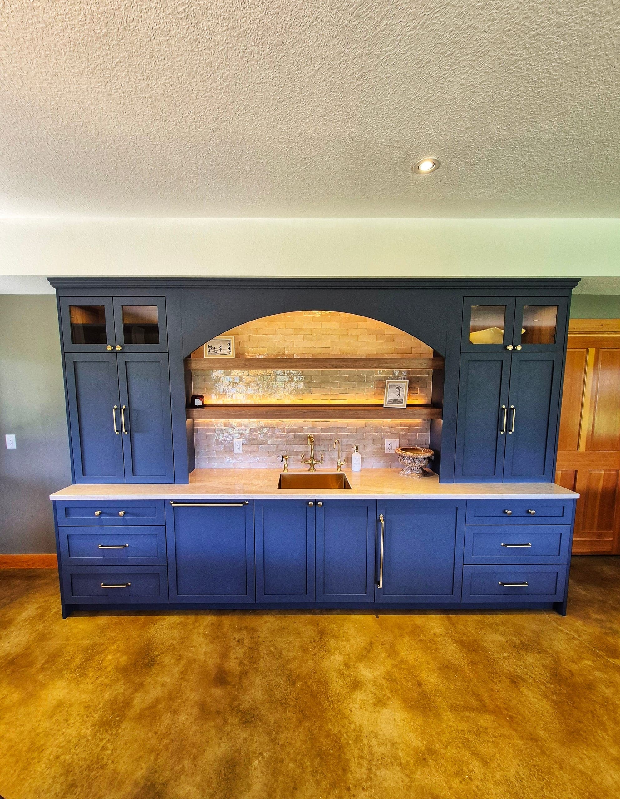 Custom-built minibar with deep-blue cabinetry, arched alcove and Italian-tile backsplash